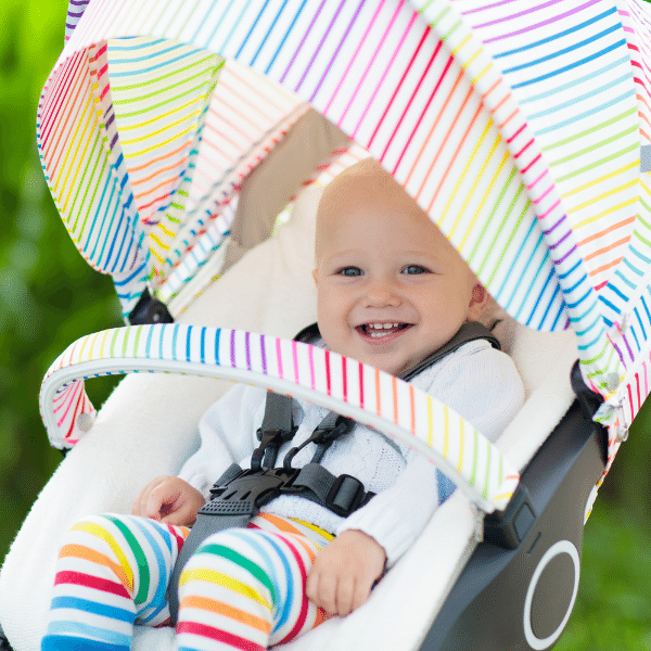 Melhores marcas de carrinho de bebê: A foto mostra um bebê com calça colorida num carrinho de bebê todo colorido.