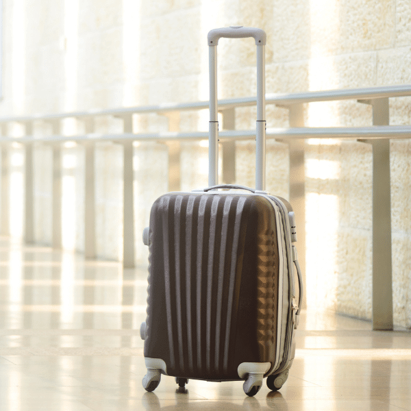 A imagem mostra uma mala de viagem marrom em um corredor.