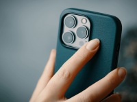 A foto mostra uma mão segurando um iphone da linha Pro com 3 câmeras