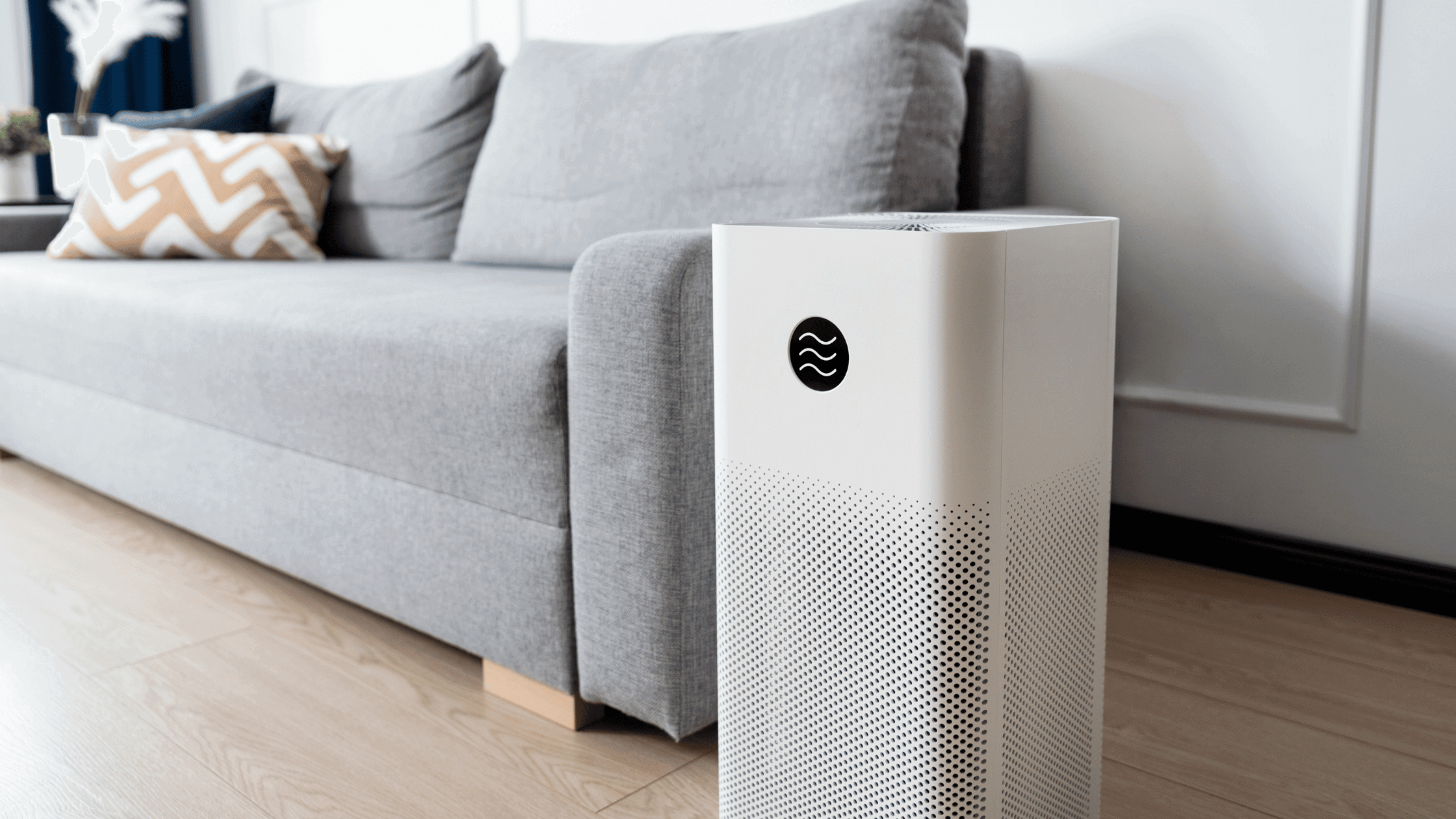 A imagem mostra um ar condicionado portátil branco em uma sala de estar.