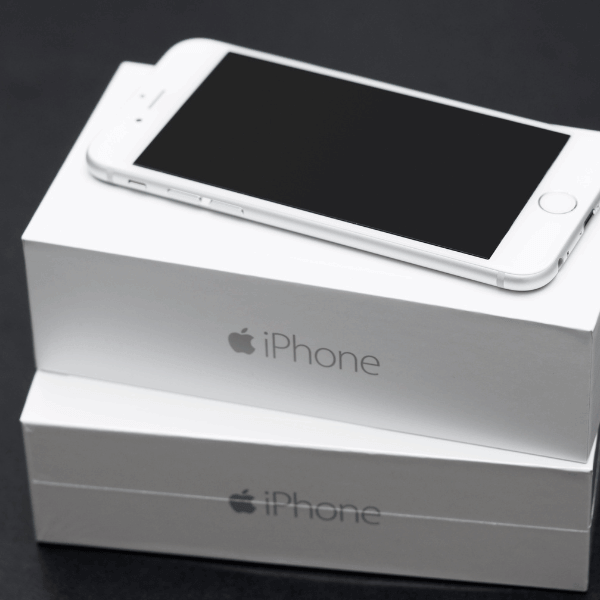 A foto mostra duas caixas de iPhone e um iPhone SE branco em cima delas, a tela está desligada.